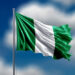 Nigeria flag flying on blur blue clouds background.
